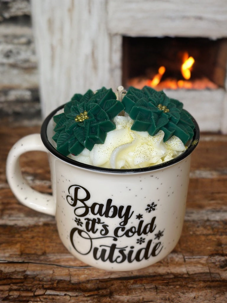 Λευκή κούπα με μάυρες κουκίδες που γράφει baby it's cold γεμάτη με φυτικό κερί σόγιας σε εφέ σαντιγύς και 2 φύλλα γκι (mistletoe leaves) σε πράσινο χρώμα