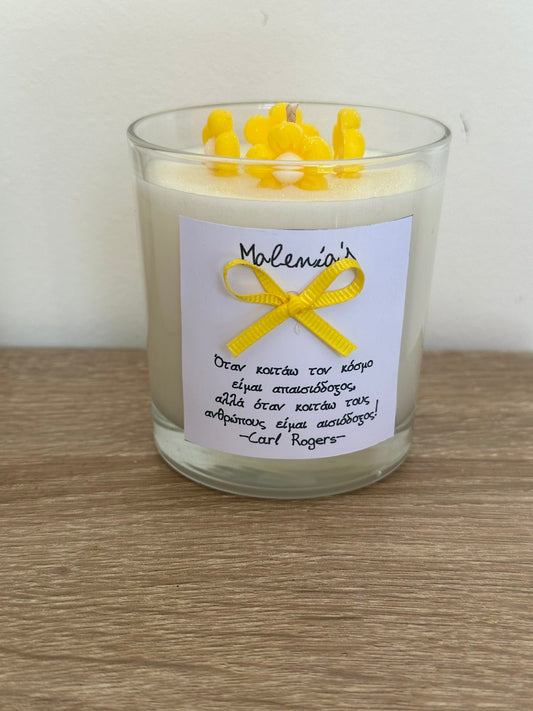 Glass Jar with Scented Candle, ellow wax flowers on top of the candle and a yellow bow with a message in front of the jar