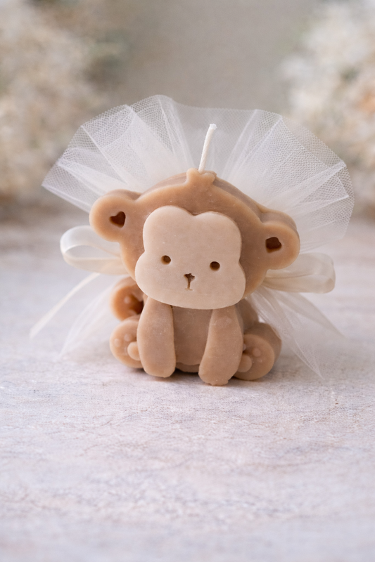 Μπομπονιέρα μαϊμουδάκι κερί , με κομψό τούλι και φιόγκο .